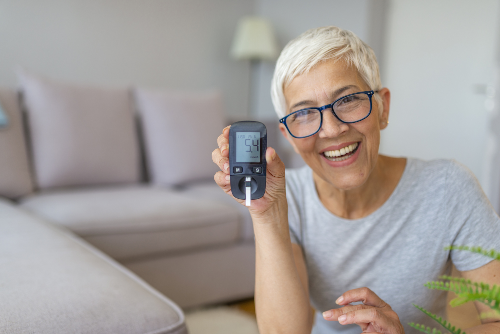 Older lady smiling as she tests her blood sugar levels