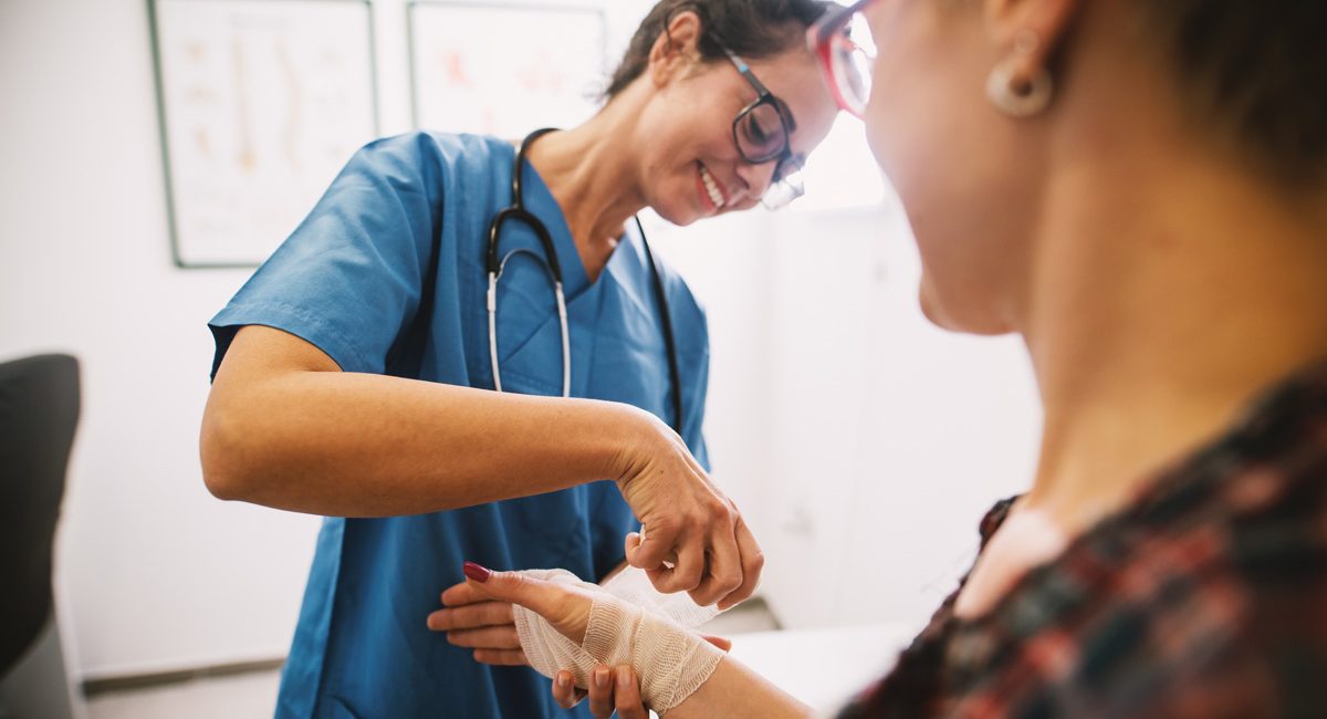 A primary care physician dressing a wound on a patient’s hand in El Paso.