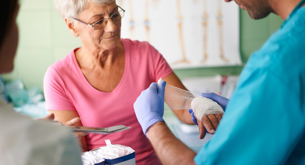 A physician wrapping a woman’s hand in gauze for wound care in El Paso.