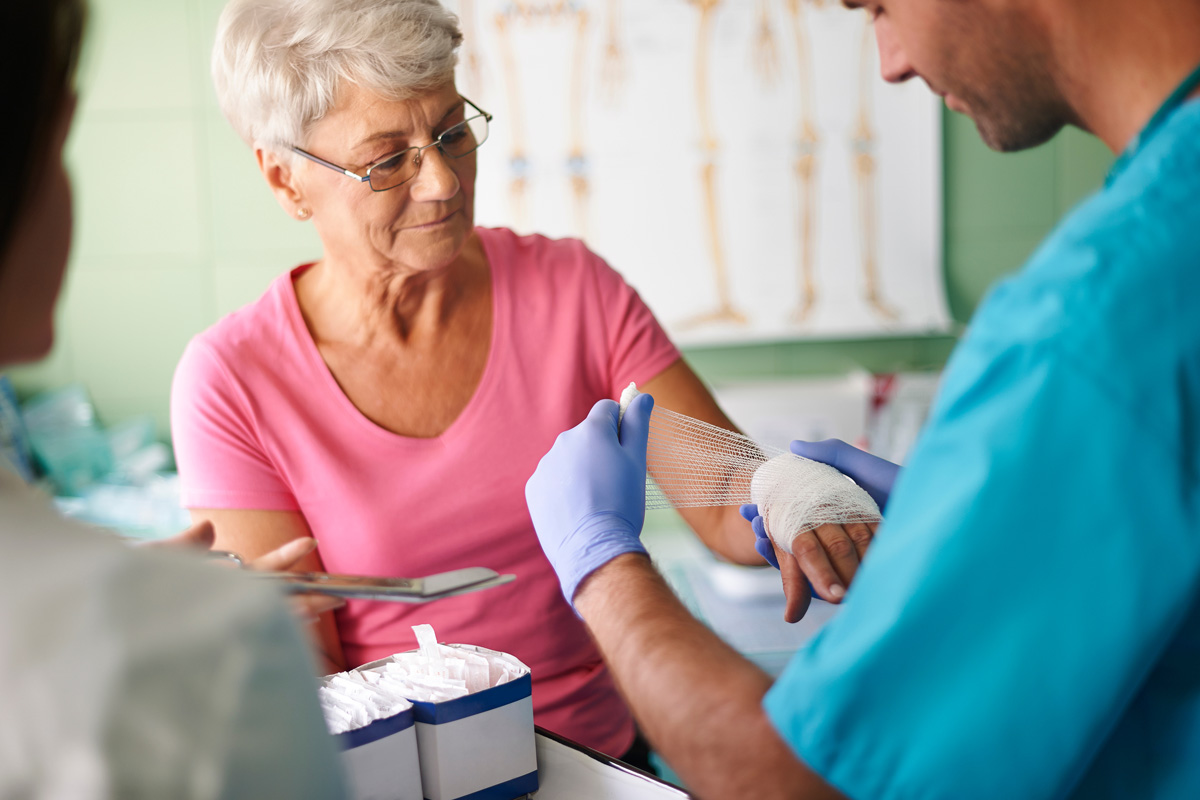 A physician wrapping a woman’s hand in gauze for wound care in El Paso.